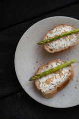 sandwich with asparagus curd cheese on a ceramic light plate on a wooden background