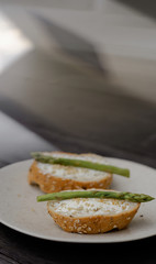 sandwich with asparagus curd cheese on a ceramic light plate on a wooden background