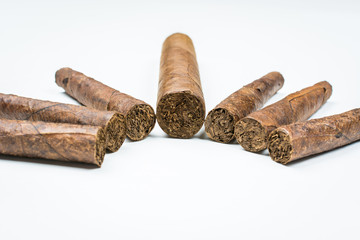 Big and small cigars twisted from sheets of tobacco on white background.