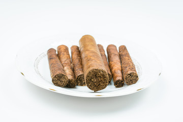 Strong cigars from twisted sheets on white saucer with white background.