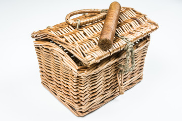 Long cigar from twisted sheets on wicker basket with white background.
