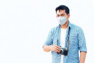 
A young Asian man standing over white background wearing a medical face mask for protects against the spread of coronavirus.