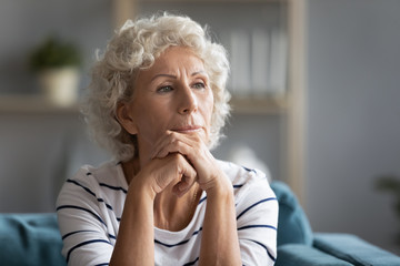 Thoughtful middle aged elder woman put head on hands, head shot. Pondering old mature grandmother recollecting memories, thinking of personal psychological health troubles, retirement life concept.