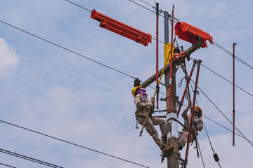 Two linesmen use insulated equipment to repair and maintain high-voltage distribution systems. The...