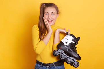 Closeup portrait of smiling woman with hand on cheek, holding roller skating in hands, has...