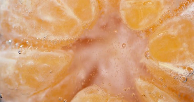 Peeled tangerine under water with air bubbles.
