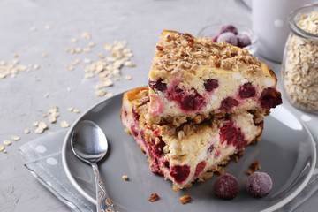 Slices of homemade cottage cheese casserole with oatmeal and cherry on a gray plate on a gray concrete background, closeup, horizontal format