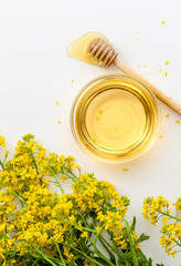 A bowl of honey with surepka flowers on a white background