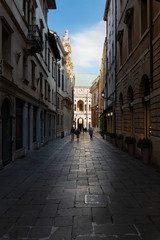 Fototapeta na wymiar Vicenza, in the afternoon the street called Contra del Monte is completely in the shade, while the Palladian Basilica is illuminated. This condition creates an interesting depth effect. Italy.