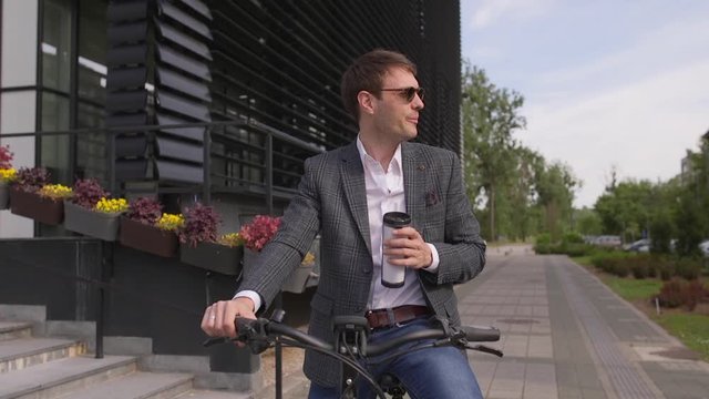 Handsome young businessman on the ebike with takeaway coffee cup