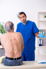 Obraz premium Old man visiting young male doctor dermatologist