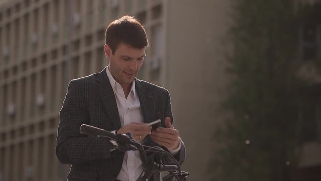 Handsome young businessman on the ebike using mobile phone