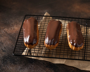delicious eclairs, covered with dark chocolate. traditional french dessert. dark concrete background. copy space.