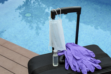 Travel suitcase, sanitizer gel or antibacterial soap, disposable gloves and medical mask. The ban on travel during the epidemic of the coronavirus and the introduction of quarantine concept.