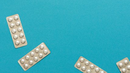 Blister packs with pills on a blue background, lowering blood cholesterol with statin tablets