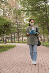 Fototapeta premium Contemporary girl in mask and smart casualwear scrolling in smartphone