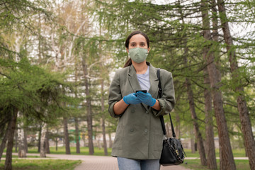 Young brunette woman in protective gloves and mask looking at you