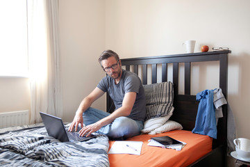 Man with headphones in working from home in bedroom