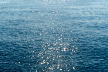 Ocean waters in calm weather. Walkway of sunlight with bright sparks on the water. Background. Abstract.
