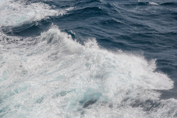 Ocean wave with a dense cap of sea foam in stormy weather. Background. Abstract.