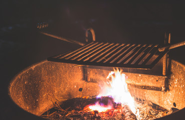  Stainless Steel BBQ Grill over bonfire im camp site in campground at night.