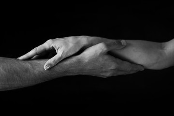 Fototapeta premium male and female hands touch each other on a dark background. close up. black and white photo