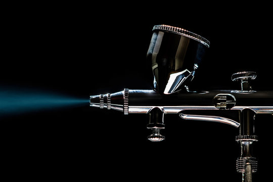 Precision painting with Airbrush using blue color by black background where the pressure is provided by a hobby compressor