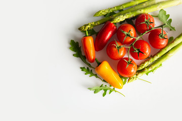 Fresh asparagus, tomatoes, bell papers and arugula isolated on a white background.