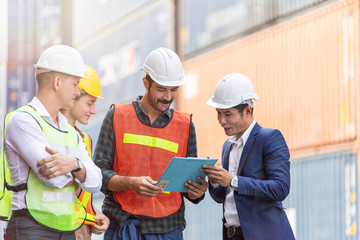 Construction workers look at clipboard while foreman discussing new project at container warehouse. Logistic shipping business work planning. corporate teamwork concept. freight cargo background