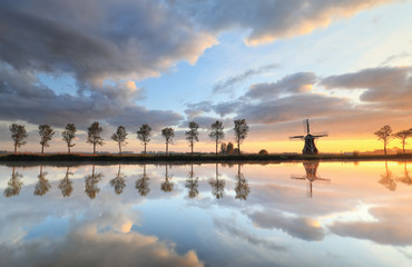 Fototapeta na wymiar beautiful sunrise over windmill and river on countryside