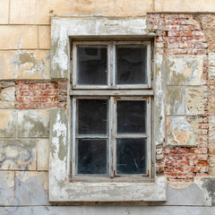 Old vintage window in a white wooden frame on a grunge damaged wall.