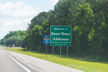 Highway road in Alabama and Mississippi border state welcome sign and text on street on interstate...