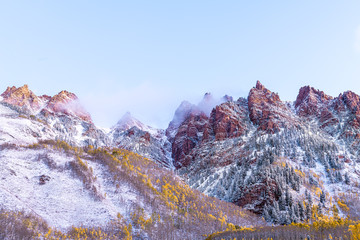 Maroon Bells sunrise in Aspen, Colorado red elk mountains with rocky mountain and snow in late autumn with winter mist fog cloud covering