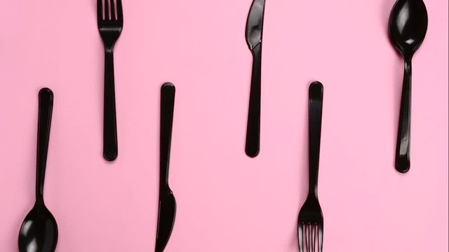 Forks, Spoons and Knives appears on pink background in stop motion. Plastic cutlery, ecology, environmental pollution by plastic, disposable tableware, waste recycling concept