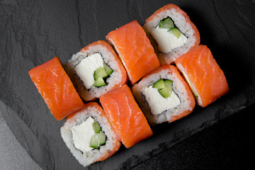 Philadelphia roll sushi with salmon on a dark background. Top view of sushi . Sushi food photo for menu.