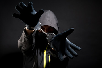 Unknown, indistinguishable thug or hucker in handcuffs and black clothes is arested. Concept: Crime...