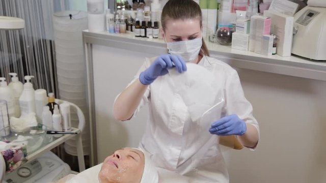 Professional unwraps paper face mask. Cosmetology.