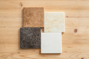 Top-down view of four marble tiles of white, black, light brown and beige colors