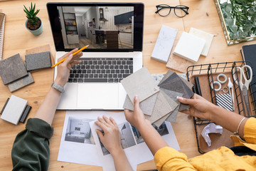 Contemporary designer pointing at home interior example on laptop display