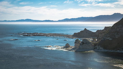 Fototapeta na wymiar Seastacks with hazy mountains in backdrop, shot in Kaikoura, New Zealand