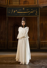 Fototapeta premium Portrait for a Sufi whirling woman dancer wearing white dress (Turkish/Semazen) performing art of Sama or physically active meditation of Sufism, and during spiritual dancing performance at Egypt