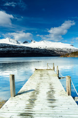 wooden pier on lake with mountains in the background