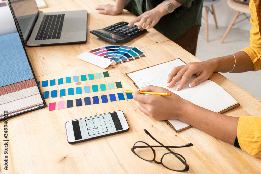 Poster young designer with pencil pointing at color swatches while making notes