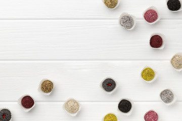 Fototapeta na wymiar Many colorful vegan candies energy balls on white wooden table