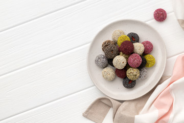 Colorful vegan candies energy balls on a plate on a white wooden table