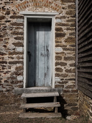 Vertical image of an old wooden light blue door on a brick stone and mortar historic building