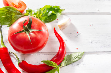 red tomatoes, chili peppers, green Basil sprigs, garlic on a white