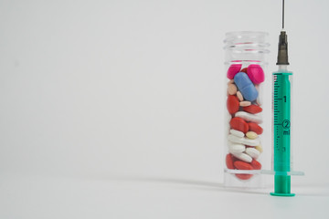 Macro view of colourful medical pills and tablets out of a drug bottle and syringe - white background with copy space.