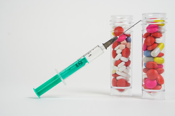 Macro view of colourful medical pills and tablets out of a drug bottle and syringe - white background with copy space.