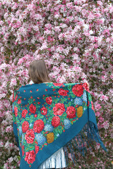 Russian fashionable girl in vintage Pavlovo Posad shawl. Pink flowers of blossoming apple-tree,...